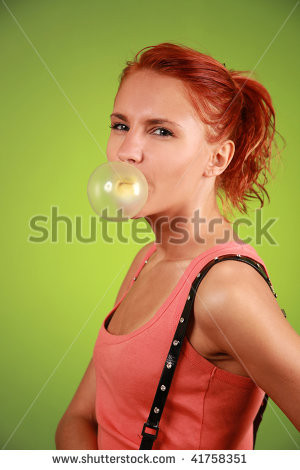 funny redhead girl with bubble gum on green background - stock photo