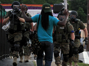 ... riot gear walk toward a man with his hands raised Monday in Ferguson