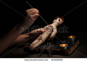 Voodoo doll girl pierced by a needle on a wooden table in the ...