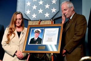 Maureen and Daniel Murphy stand next to a framed picture and Medal of ...