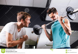 ... Free Stock Image: Young man motivating gym buddy during bicep exercise